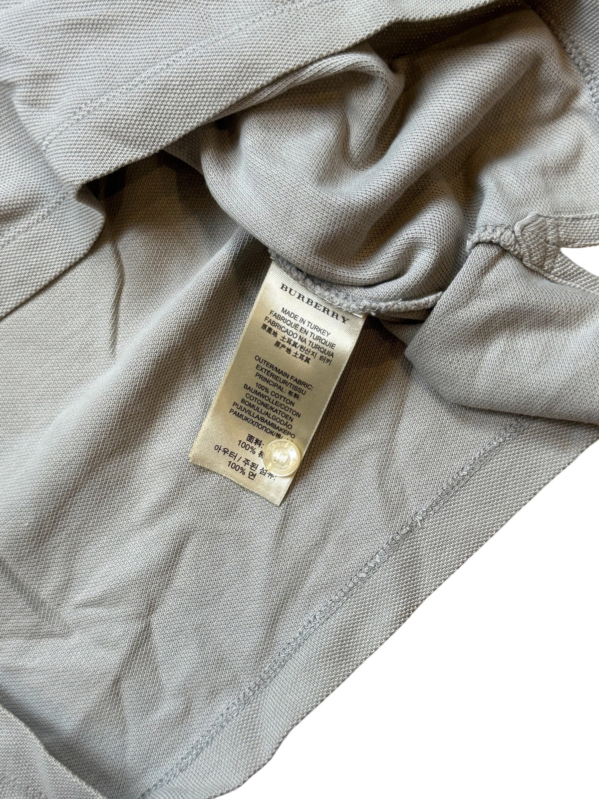 Archive No.9 Burberry polo shirt interior care label showing 100% cotton composition and grey textured fabric