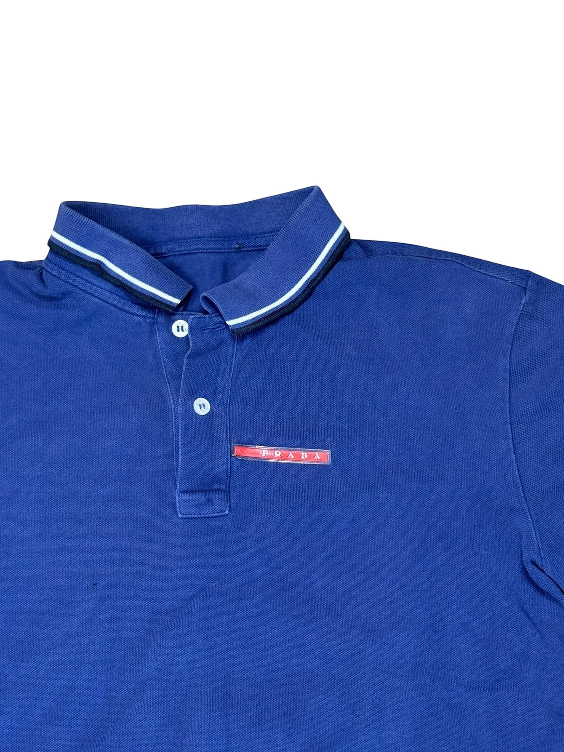Archive No. 9 navy blue 100% cotton Prada polo shirt with red logo badge on chest and striped collar. Size L.