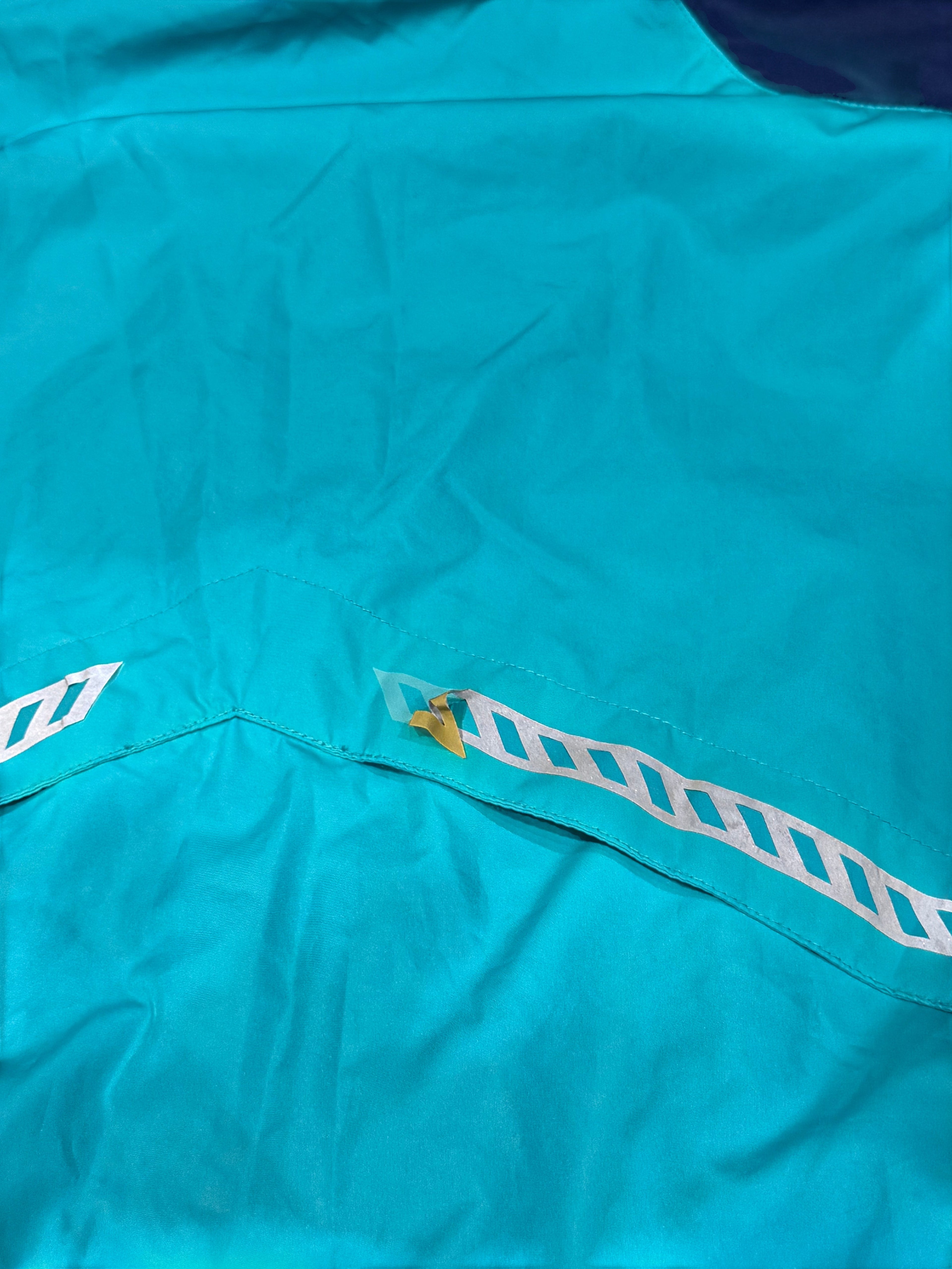 Archive No. 9 Nike windbreaker in turquoise and purple, size Large. Lightweight, waterproof, and wind-resistant with reflective detailing.